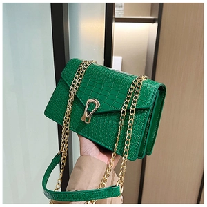 Detail of bright green crocodile embossed bag with gold U-shaped lock and chain strap