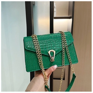 Detail of green crocodile texture handbag featuring a unique golden U-shaped metal lock