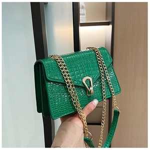 Close-up of bright green crocodile pattern leather bag with golden horseshoe lock