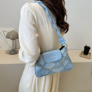 Détail du sac bandoulière bleu clair en denim avec sangle tressée et chaîne à fleurs