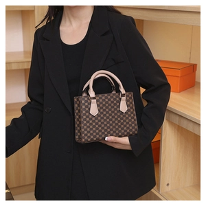 Close-up of a vintage brown checkered tote bag with ivory leather handles and metal details