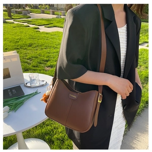 Borsa a tracolla in pelle marrone con logo in metallo dorato e ciondolo a forma di orso