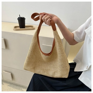 Detail of hollow-out straw woven handbag with brown leather handles for summer beach style