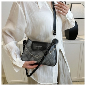 Détail d'un sac en denim à carreaux gris avec rabat en cuir noir et chaîne argent