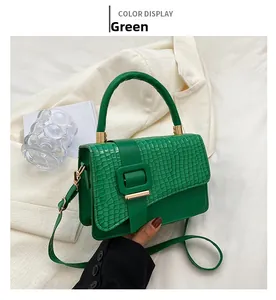 Detailansicht einer grünen Handtasche mit Krokodilmuster und großer quadratischer Schnalle