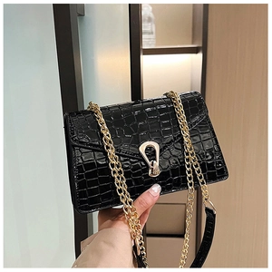 Detail of black crocodile-embossed leather texture and gold horseshoe buckle closure