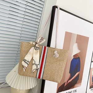Detail of colorful striped straw tote bag featuring white cotton rope handles and silk scarf