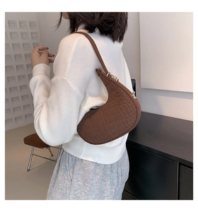 Close-up of brown crescent underarm bag featuring premium crocodile pattern texture