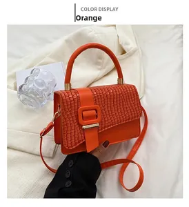 Detailaufnahme der orangefarbenen Handtasche mit Webmuster und quadratischer Schnalle