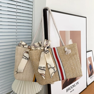 Detail of colorful striped straw tote bag with cotton rope handles and silk scarf accent