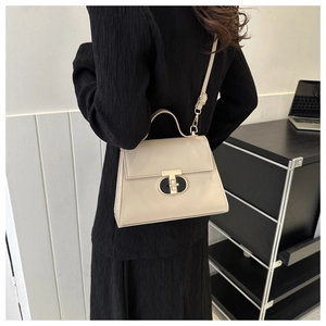 Vista dettagliata della borsa in pelle beige con elegante chiusura metallica a T dorata