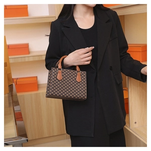Close-up of a vintage brown checkered handbag with leather handles and gold metal accents