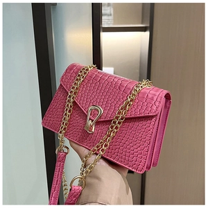 Macro view of rose red faux crocodile leather texture and golden metal lock on handbag