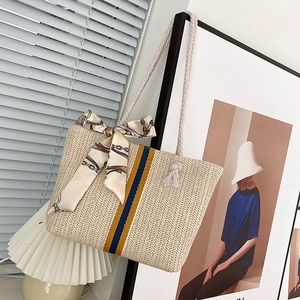 Detail of hand-woven straw tote with navy yellow stripes and silk scarf handle accent