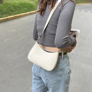 Borsa hobo beige minimalista portata a spalla da una modella in un ambiente esterno
