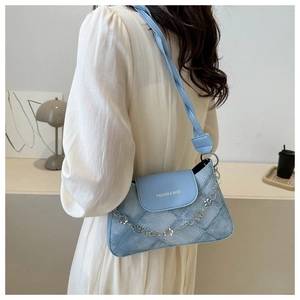 Détail du sac à bandoulière bleu ciel en denim avec chaîne fleurie et logo brodé