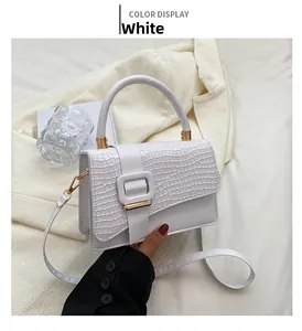 Detailansicht einer weißen Handtasche mit Krokodilmuster, eleganter Schnalle und Goldakzenten