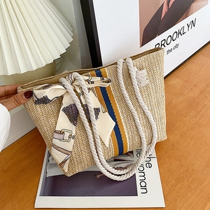 Close-up of woven straw tote with blue stripes, cotton rope handles, and floral scarf detail