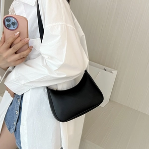 Dettaglio di una borsa hobo in pelle nera opaca abbinata a una camicia bianca casual