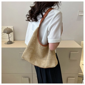 Detail of woven straw shoulder bag featuring brown leather trim and hollow mesh texture