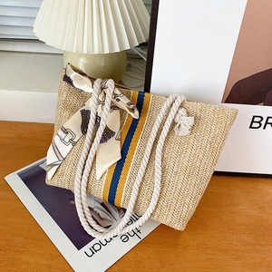 Macro view of woven straw tote bag with cotton rope handles and colorful striped ribbon