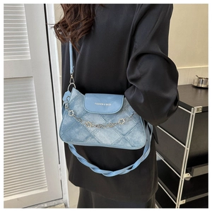Détail du sac bandoulière bleu clair avec chaîne à fleurs argentées et texture denim