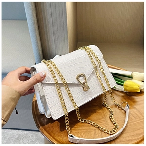 Detail of white crocodile pattern shoulder bag with gold horseshoe lock and chain strap
