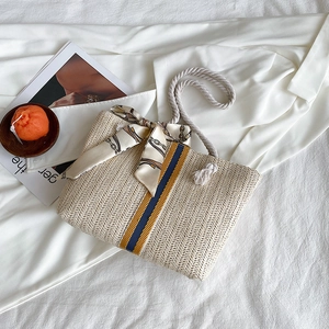 Detail of colorful striped woven tote with cotton rope handles and silk scarf accent