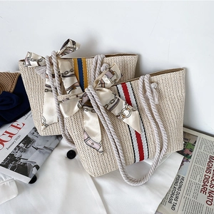 Detail of woven straw tote bags with colored stripes and cotton rope handles for beach