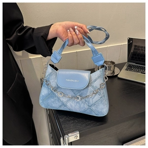 Détail du sac à main bleu clair texture denim avec chaîne à fleurs et texte fashion