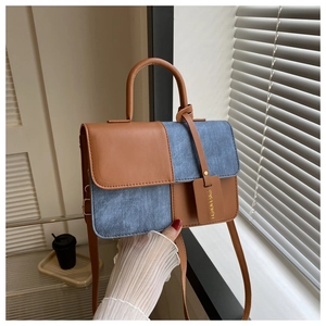 Détails du mini sac bicolore montrant le similicuir marron et la texture denim bleu