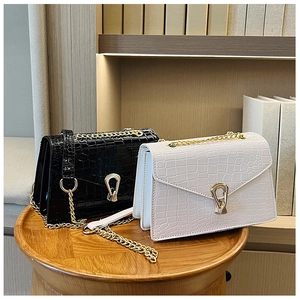 Detail of elegant black and white crocodile pattern crossbody bags with gold chain straps