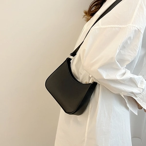 Modella che indossa una borsa a mezzaluna nera con trama litchi e tracolla in pelle