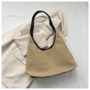 Detailed knit pattern of beige woven tote bag with contrasting black leather trim