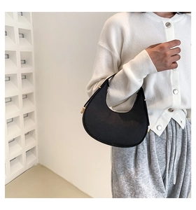 Close-up of minimalist black nylon crescent hobo bag with gold zipper detail on model