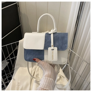 Détail des coutures contrastées en denim bleu et cuir blanc sur le petit sac à bandoulière