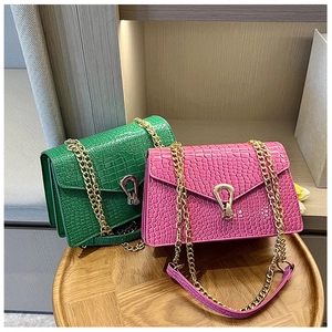Detail of green and pink crocodile pattern crossbody bags with gold horseshoe locks