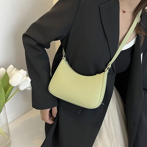 Borsa hobo verde chiaro indossata da una modella con blazer nero e gonna bianca