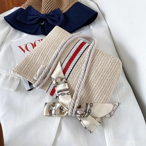 Detailed view of beige woven straw tote with colorful stripes and chic silk bow detail