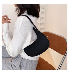 Detail of minimalist black crescent shoulder bag with golden metal hardware adjusters