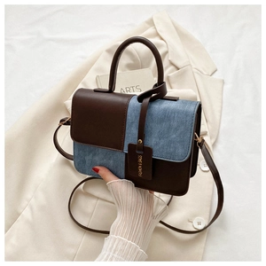Détail du sac à bandoulière en patchwork de cuir marron et de denim bleu avec étiquette