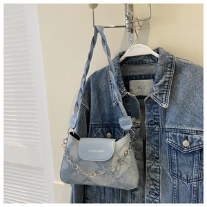 Détail du sac bandoulière en denim bleu clair avec surpiqûres et chaîne fleurie