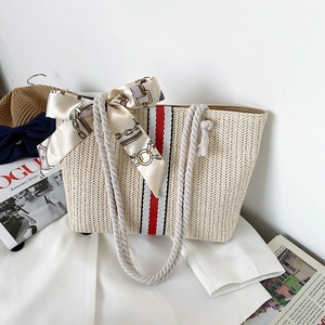 Detail of straw tote bag with red stripes, rope handles and a silk scarf accent