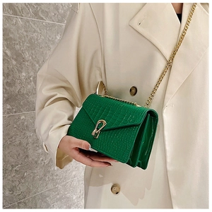 Close-up of green crocodile embossed bag with gold horseshoe buckle and chain strap