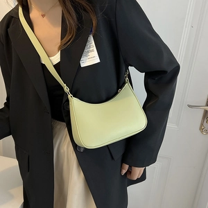 Foto lifestyle della borsa a tracolla a mezzaluna verde chiaro abbinata a un blazer