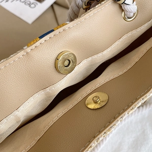 Close-up of magnetic snap closure on straw tote bag with decorative geometric silk scarf