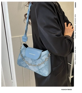 Détail du sac sous le bras en denim bleu clair avec chaîne fleurie et bandoulière