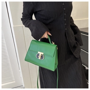 Dettaglio borsa a mano in pelle verde con chiusura girevole oro e texture