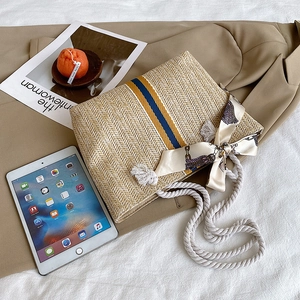 Detail of colorful striped straw tote bag with silk scarf and white cotton rope handles