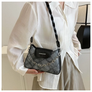 Détail du sac matelassé gris avec rabat en cuir noir et chaîne à fleurs argentées